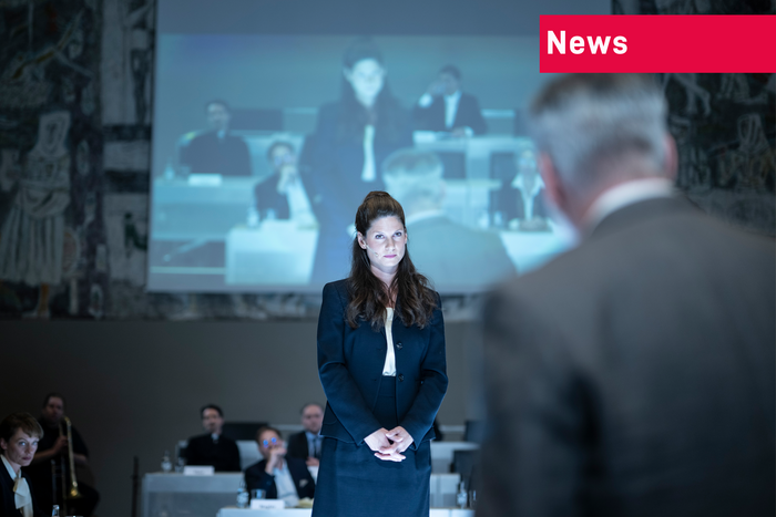 Eine Aufnahme aus dem Stück: Es zeigt die Figur der Rechtsprofessorin vorne, der Präsident FMH hat uns den Rücken zu gedreht.